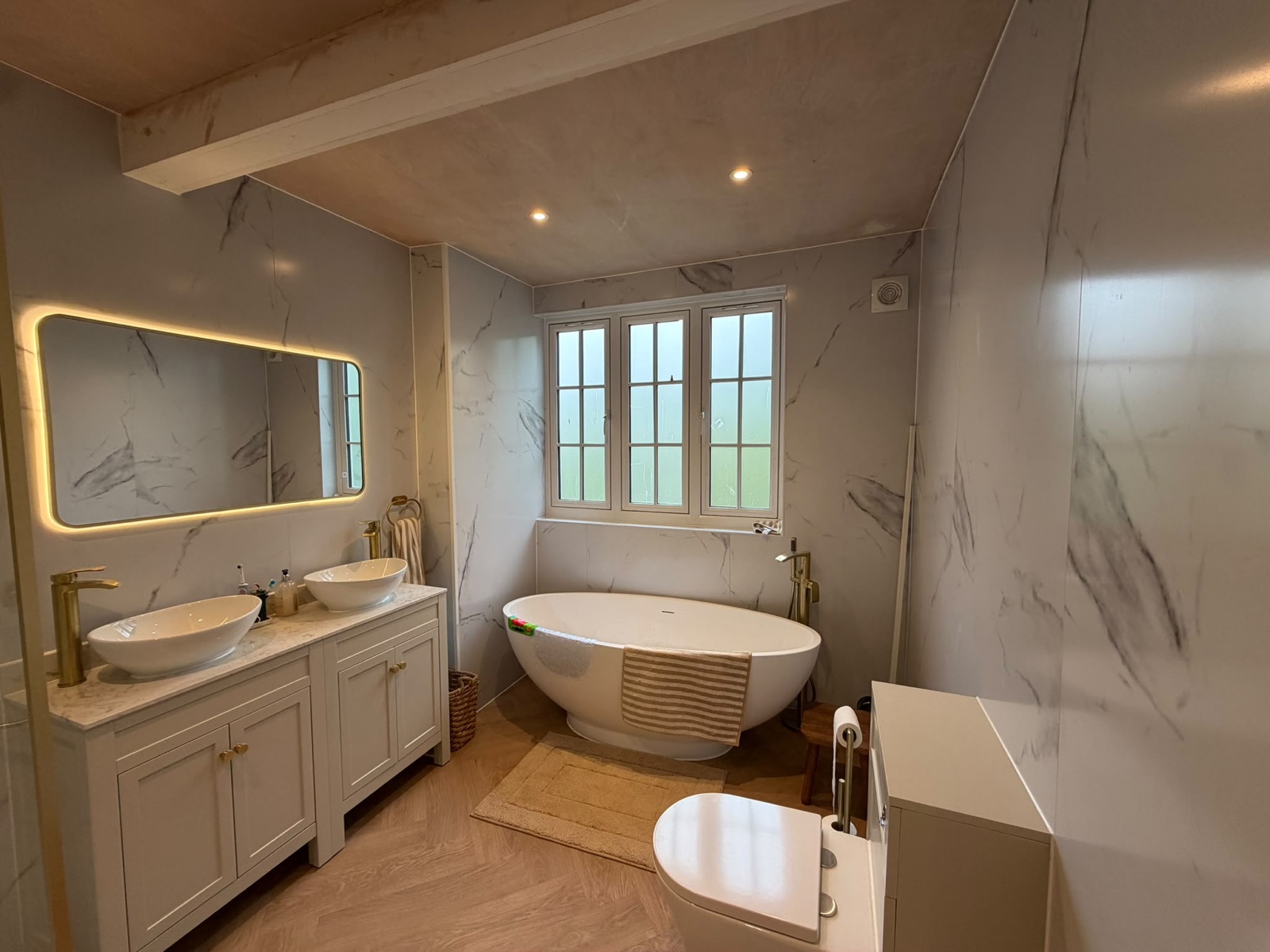 Bathroom with backlit mirror, freestanding bath and downlights