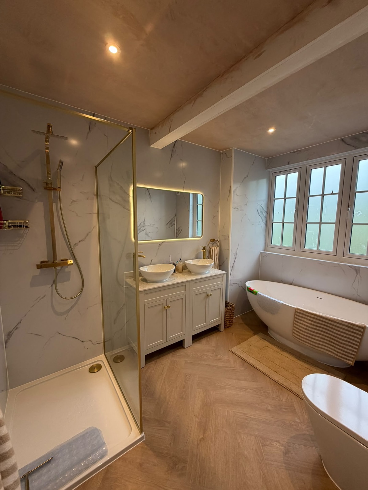 Bathroom with walk-in shower, freestanding bath and backlit mirror