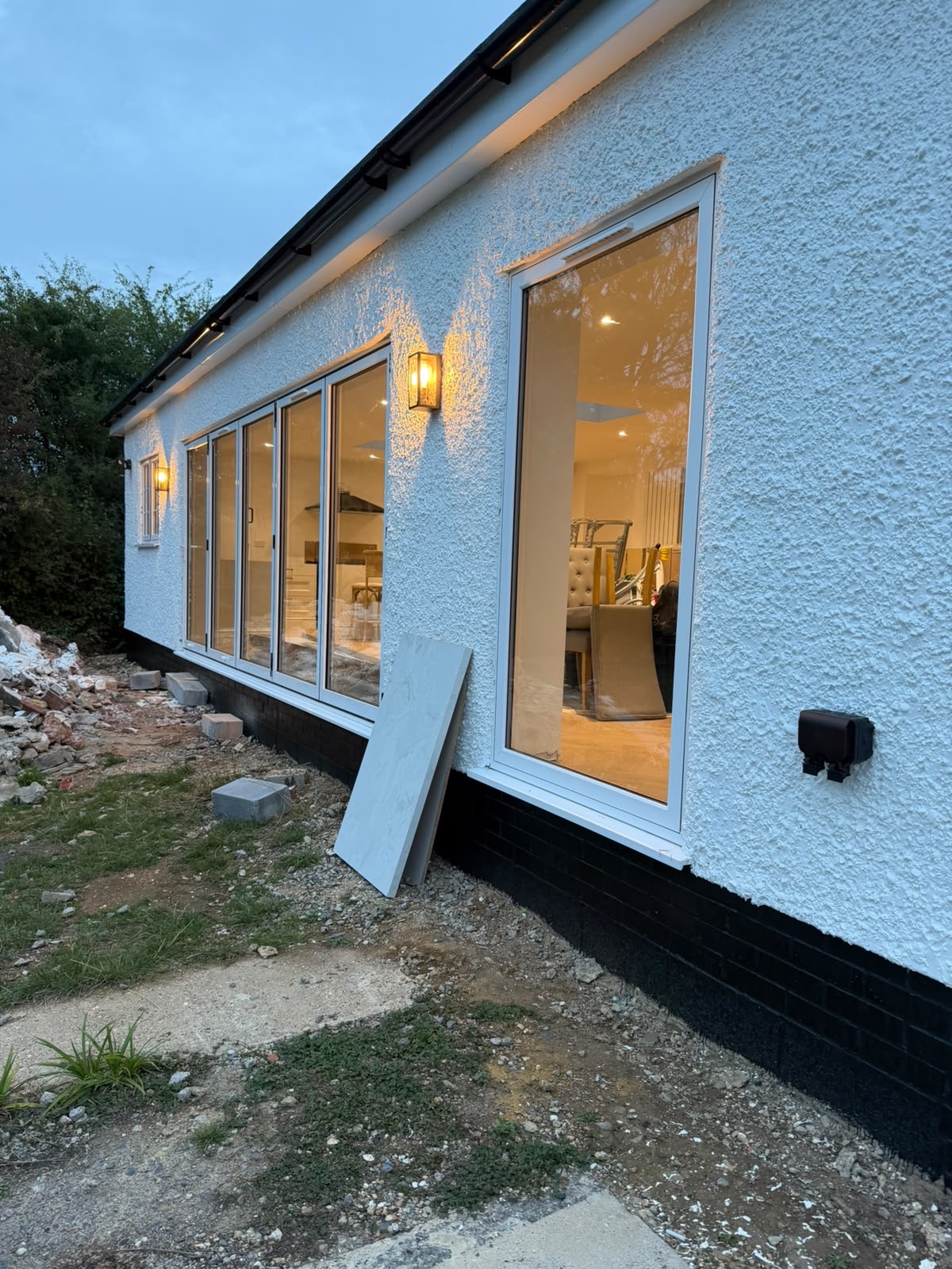 House at dusk with lit windows and exterior wall lighting